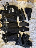 Photo showing multiple black mesh bags each containing a pair of Bare diving gloves, and two pairs of black MEC diving boots size 10.