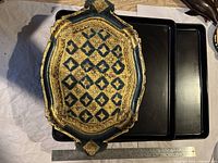 Photo of an intricate vintage Indian wooden serving tray with blue and gold decorative pattern, showing details of design and missing foot.