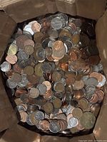 Overhead view of cardboard box filled with mixed US pennies, nickels, and dimes