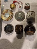 Top down view of all nine pieces including the decorative plate, hanging metal bell, and varied Asian pottery items.