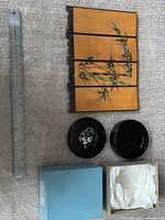 Small privacy screen and black lacquer dish placed together with ruler for size reference, blue box with tissue paper next to the dish