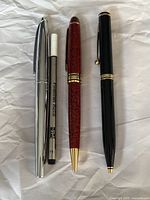 Full view of three pens aligned with one refill; silver Cross pen, red Cadence pen, black Shaeffer pen, and fineliner refill