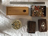 Top view of five collectible boxes arranged on a white surface with a ruler for scale