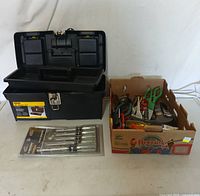 Photo showing black metal toolbox, cardboard box with assorted hand tools, and sealed Husky screwdriver set