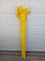 Yellow beach umbrella fully folded and contained in the long yellow fabric carry bag.