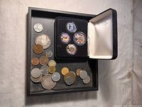 Overview of assorted coins alongside the display case insert holding four colorized Obama commemorative coins