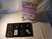 Photo of crystals placed in a black display tray and the book 'Crystals Color & Chakra' behind.