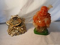 Both good luck statues showing the Buddha and frog side by side for scale and detail.