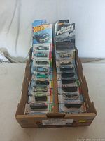 Two rows of Hot Wheels cars in original blister packaging inside a display box, some Fast & Furious themed cars visible