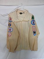 Front view of yellow women's flight windbreaker with visible patches on both sleeves, hanging on a white hanger against a white background.