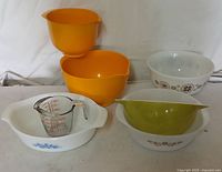 Photo showing all six mixing bowls and one measuring cup arranged together. Various colors and designs visible.