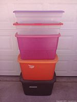 Stack of five plastic storage containers in varying colors and sizes, showing overall lot contents.