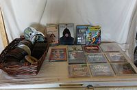 Wide view showing basket of loose discs next to 10 unopened media discs in cases spread out on table.