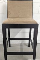 Front view of a wood bar height chair with beige microfiber upholstered seat and backrest against a white wall.