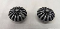 Close up front view showing design of two round metal cabinet knobs with grooved ribbing and central button detail.