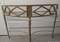 Front view of the half moon console table showing the detailed metal frame with geometric patterns and legs.