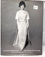 Book front cover showing black and white photo of Jacqueline Kennedy wearing an elegant short sleeve dress with tied waist detail.