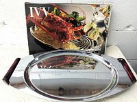 Chrome tray with cherry red Bakelite handles and shiny surface, oval shape.
