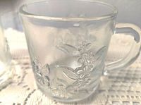 Close-up showing embossed floral pattern on the clear glass mug.