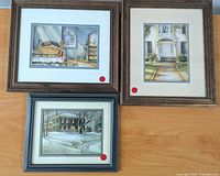 Three framed prints resting on wood floor, two with red dots indicating included items