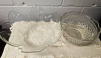 Top view of two glass bowls showing one six-petal flower shaped clear glass bowl and one Wexford pattern compote bowl.