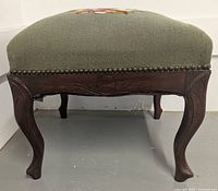 Front view showing carved walnut legs and nailhead trim of needlepoint cushion