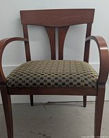 Front view of wood chair showing the wide upholstered seat with checkered fabric and wood frame with armrests and backrest.