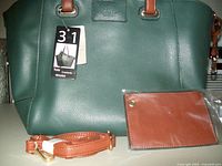 Front view of deep blue tote bag with tan straps, tag reads 3 in 1 Tote, Crossbody, Wristlet