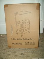 Box displaying illustration of 3 tier utility rolling cart including shelves and wheels