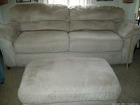 Frontal view of beige microfiber sofa and matching ottoman, showing overall structure and condition.