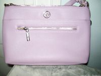 Front view of pink Anne Klein purse showing zippered front pocket with silver zipper pull and logo emblem.
