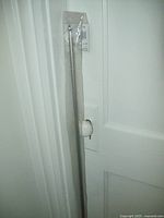 Full length view of the silver metallic finished cafe rod still in packaging, hanging on door handle.