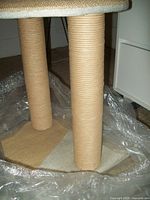 Close-up of two vertical posts wrapped in sisal rope and the square base for the cat scratcher and perch.