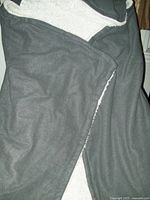 Gray hooded snuggle blanket showing the microfiber exterior and hood, folded with visible seams and hood construction.