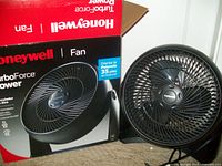 Fan placed next to its original box, showing product and branding details.