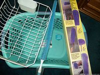 Teal laundry basket, blue bristle brush, and purple magnetic duster set in package.