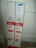 Two boxed Project Source cordless vinyl mini blinds standing upright against a white door, showing brand and product on front.
