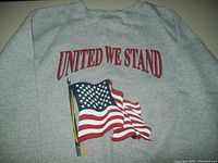 Front of gray sweatshirt with "UNITED WE STAND" in red text and American flag graphic.
