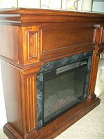 Front angle view of solid oak wood electric fireplace with ornate molding and fluted side accents, with visible electric flame display and dark surround.