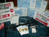 Various components laid out showing radio transmitters, DVDs, brochures, signs, sign stands, microphone, stickers