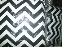 Close-up of black and white chevron pattern throw pillow covers in plastic wrapping showing design and texture.