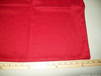 Close up photo showing red fabric of pillow cover and ruler indicating size approximately 18 inches.