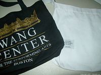 Photo showing black canvas tote bag with gold Wang Center print and plain white canvas tote bag side by side