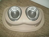 Top view showing two stainless steel bowls fitted in beige plastic elevated holder with a rubber base mat underneath.