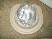 Top-down view of the beige elevated pet food center with covered stainless steel bowl wrapped in plastic labeled Pet Comfort