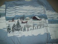 Front view of light blue sweatshirt showing detailed winter scene print including snow, trees, farmhouse, barn, fence, and horse-drawn sleigh.