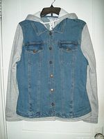 Front view of women's blue denim and grey fleece jacket with hood, hanging on hanger