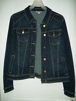 Front view of the women's denim jacket hanging on hanger, showing button front, chest pockets with flaps, and side pockets.