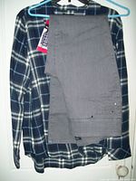 Full view of gray stretchable pull-on jeans laid over blue and gray plaid flannel shirt on hanger.