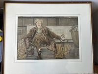 Full front view of framed artwork showing the man sitting on a bench with bags and doll.